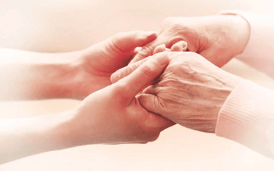 Hands of a caregiver and a senior citizen holding each other.