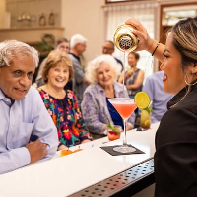 Staff serving drinks to smiling residents at the bar.