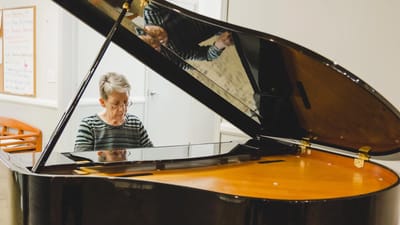 Senior playing piano in a warm, inviting room.