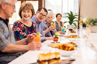 Seniors enjoying food and drinks in a dining setting.
