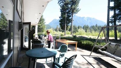 Resident grilling on a patio with trees and mountains
