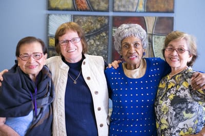 Four residents smiling together in a common area.
