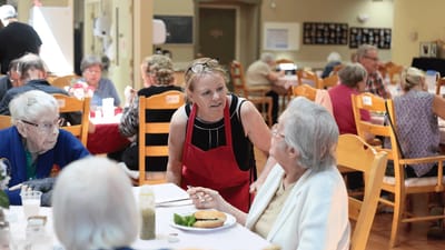Staff member engaging with residents during meal time.