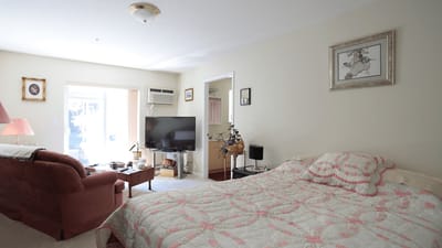 A furnished resident room with a bed and television.