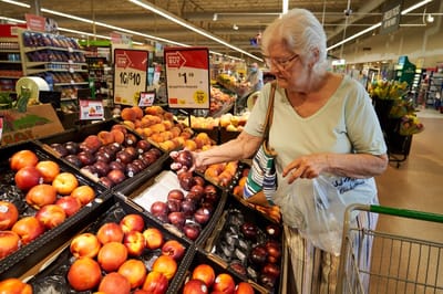 Senior woman shopping for fresh fruits in a grocery store.