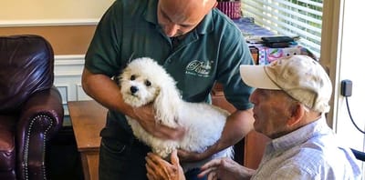Staff member interacting with a resident and a dog.