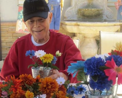 Resident arranging colorful artificial flowers outdoors.