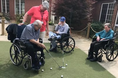 Residents playing golf on an outdoor putting green.