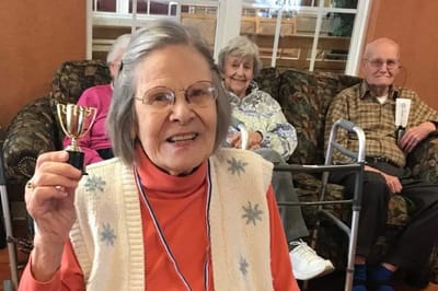 Resident celebrating with a trophy in the common area.