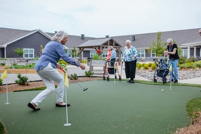 Residents enjoying a putting green activity outside.