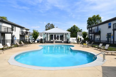 Outdoor pool area with seating and a facility building