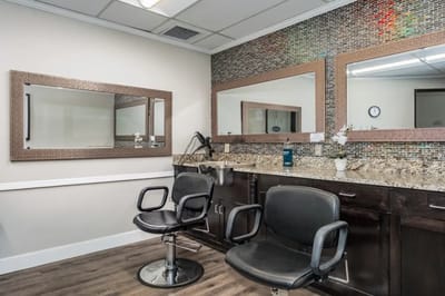 Salon area with black chairs and mirrors