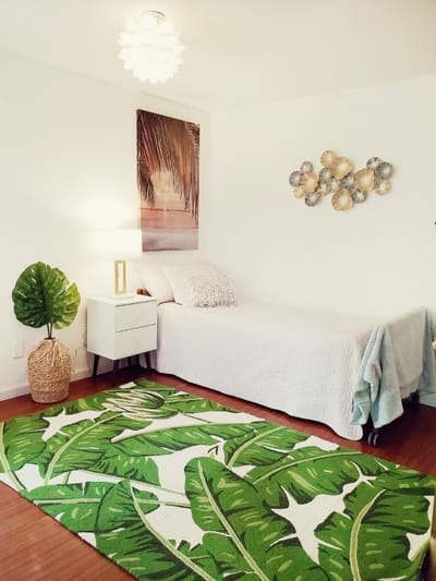 Brightly decorated private resident room with a bed and plant decor