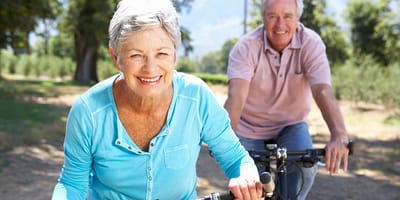 Two seniors biking together in an outdoor setting