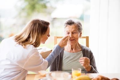 Nurse assisting an elderly woman during mealtime