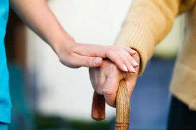 A caregiver assisting an elderly resident with a cane
