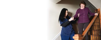 Staff assisting a resident on stairs in a facility setting