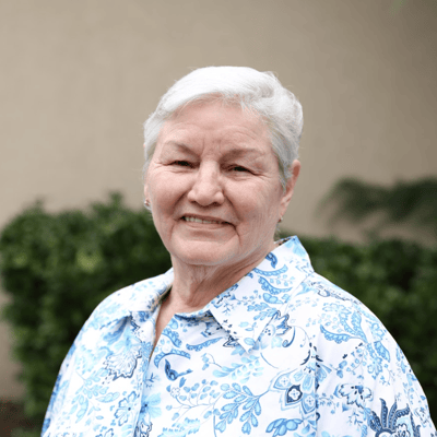 Smiling elderly woman in a floral shirt outdoors