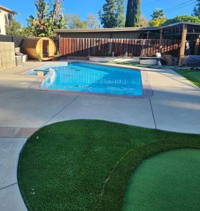 Outdoor pool area with a lawn and landscaping