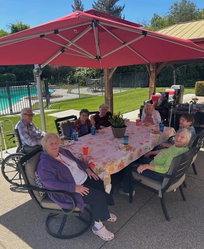 Residents enjoying time under a covered patio by the pool