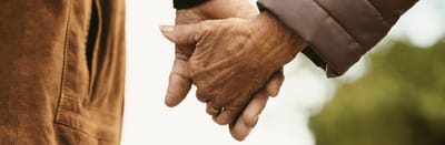 Two elderly hands holding each other outdoors
