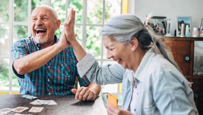 Two seniors joyfully playing cards together
