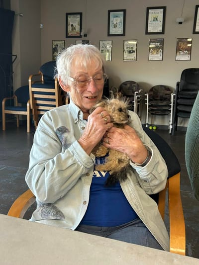 Resident happily holding a small dog indoors
