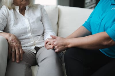 Caregiver holding hands with a resident on a couch