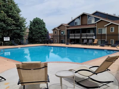 Swimming pool area with lounge chairs and buildings in the background