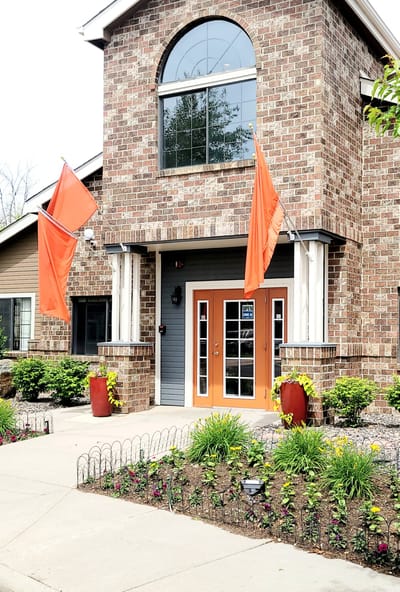 Front entrance of a senior living facility with orange flags