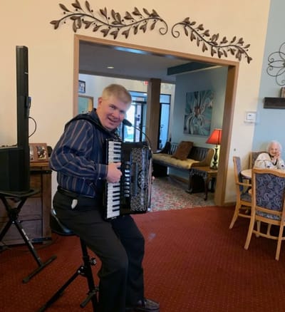 Man playing accordion while a woman enjoys music in the background