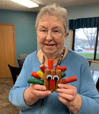 Resident holding a colorful handmade turkey craft