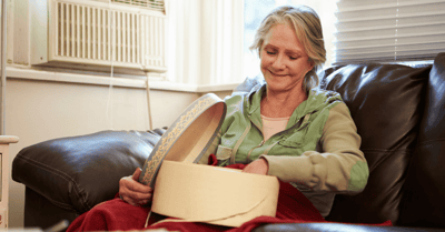 Resident smiling while opening a box on a couch