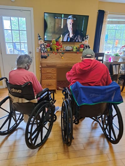 Residents in wheelchairs watching television in a common space