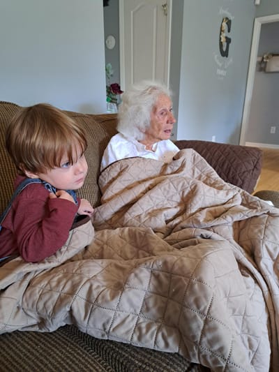 An elderly woman and a child watching TV together
