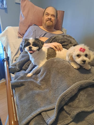 Resident relaxing in bed with two dogs