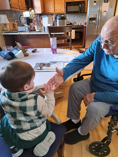 An elderly man interacting with a young child at a table