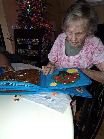 An elderly woman engaging with a sensory book indoors