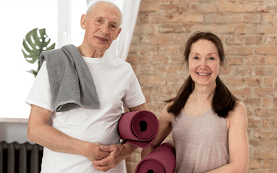 Seniors holding yoga mats in a bright studio
