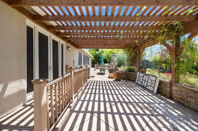 Covered patio area with seating under wooden trellis