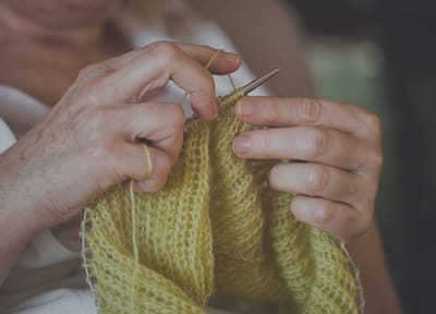 Elderly resident knitting a yellow scarf