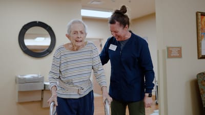 Resident assisted by staff in a hallway