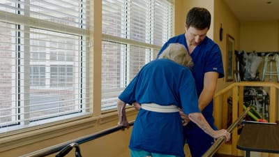 Staff assisting a resident with mobility in a well-lit hallway