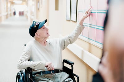Resident in wheelchair pointing at a bulletin board