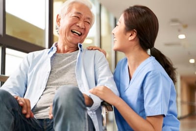 Riverside Manor, nursing home in Ames, IA — Caregiver laughing with a senior resident in a hallway