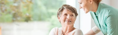 Riverside Manor, nursing home in Ames, IA — Senior caregiver interacting with smiling elderly resident