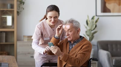 Riverside Manor, nursing home in Ames, IA — Caregiver assisting a senior man with a smartphone