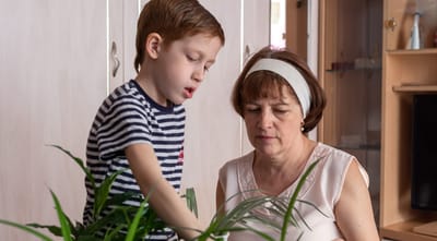 A woman and a child tending to a plant indoors.