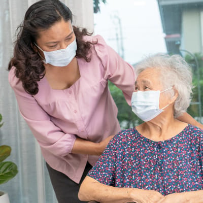 Riverside Manor, nursing home in Ames, IA — Caregiver assisting an elderly woman in a cozy setting