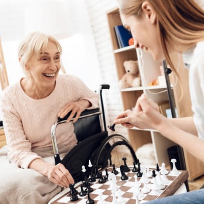 Riverside Manor, nursing home in Ames, IA — Two women playing chess in a cozy room